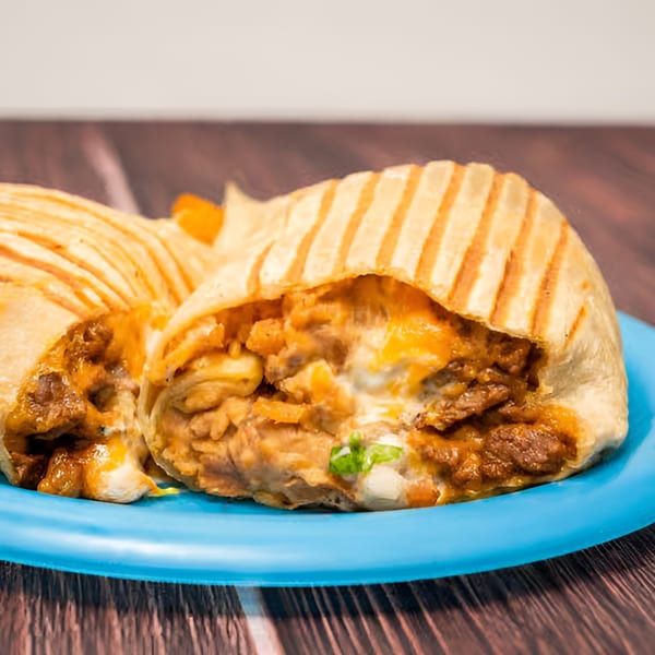 Two grilled burritos, one cut open to show meat, cheese, and rice filling, on a blue plate.